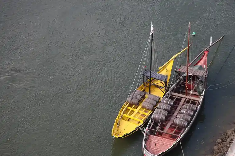Two traditional wooden river boats moored side by side on dark water, seen from above