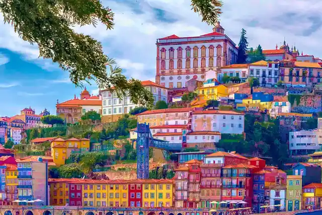 Tiers of coloured houses climbing the riverbank in Porto under a bright sky